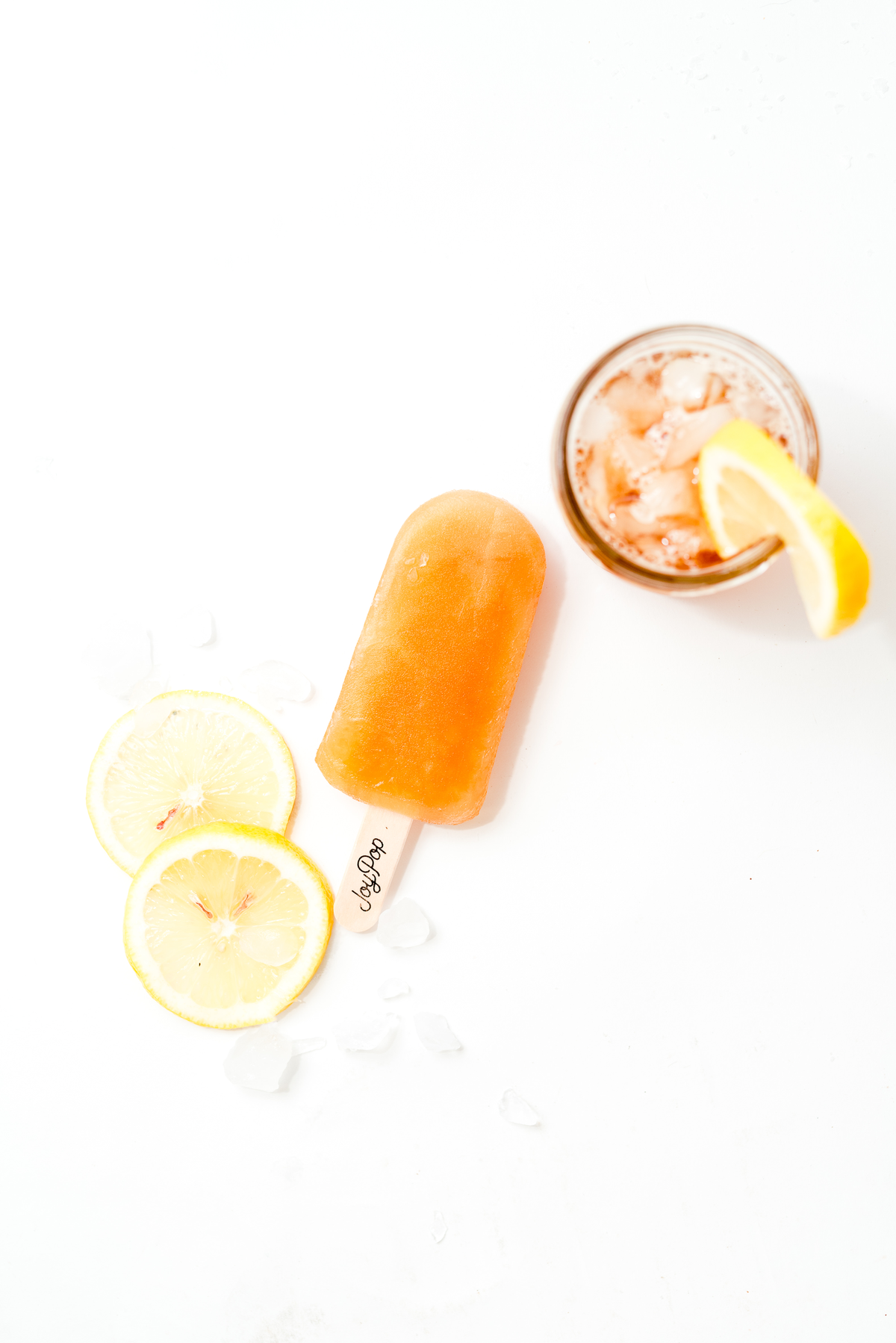 Arnold palmer pop next to lemon wedges and an arnold palmer on a white background